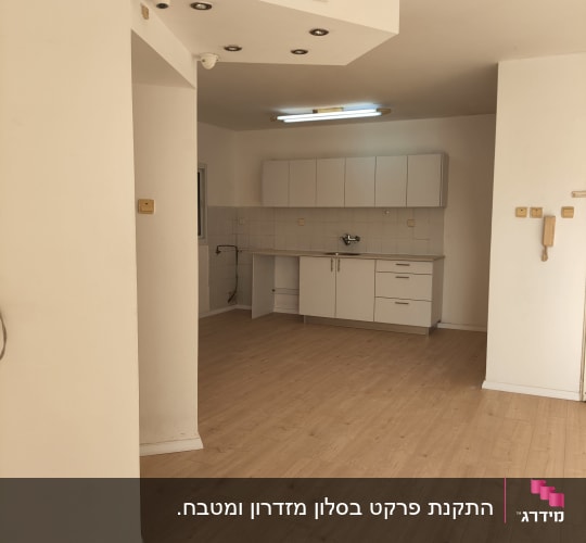 רצפת פרקט עץ בהירה בחדר ריק עם מטבח